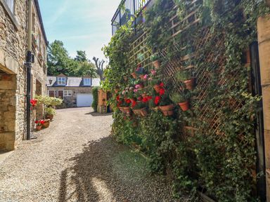 A gravel courtyard with potted plants and climbing ivy on walls at Shaftoe Mews in Haydon Bridge