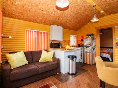 A living room with a sofa and kitchen area at Ava Lodge in West Mains near Haggerston