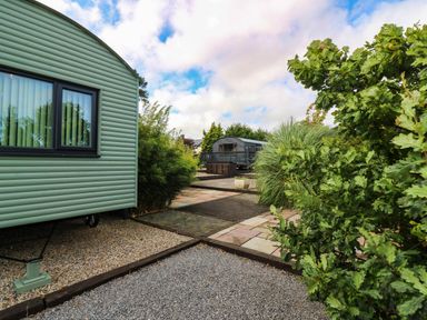 An outdoor area with a touring caravan and plants at Masons Hut West Mains near Haggerston