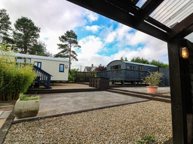 An outdoor space with caravans and a wooden deck at Masons Hut in West Mains near Haggerston