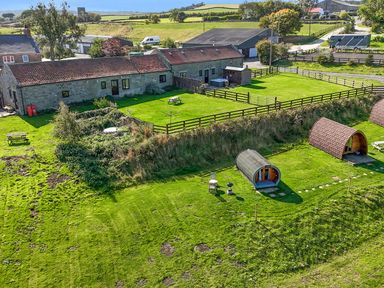 An outdoor area with buildings, picnic tables and glamping pods at Mini pod Staintondale near Burniston