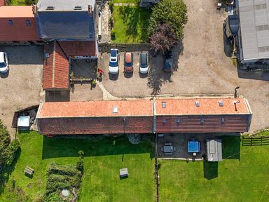 An outdoor area with buildings, cars, and a hot tub at Mini pod Staintondale near Burniston
