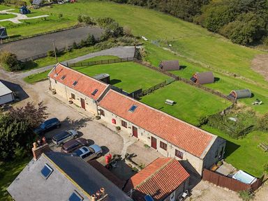 An exterior view of a property with lawn and small buildings at Mini pod Staintondale near Burniston