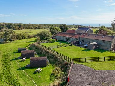 An outdoor area with picnic tables and buildings at Mini pod in Staintondale near Burniston