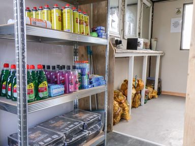 A utility room with shelves holding cleaning supplies and a worktable at Mini pod Staintondale near Burniston