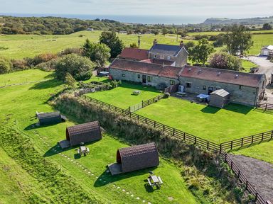 A garden area with huts and a house at Woodpeckers Shepherds hut Staintondale near Burniston