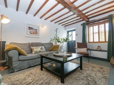 A living room with a sofa and coffee table at Elm Cottage in Moreton-In-Marsh