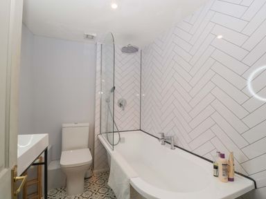 A bathroom with a bathtub and toilet at Elm Cottage Moreton-In-Marsh