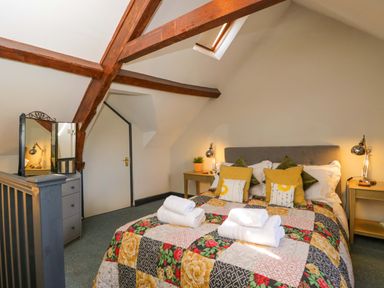 A bedroom with a bed and mirror at Elm Cottage Moreton-In-Marsh