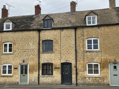 A stone building with front doors and windows at Elm Cottage in Moreton-In-Marsh