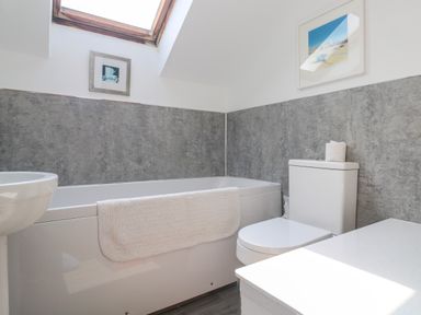 A bathroom with a bathtub, toilet, sink, and towel at The Cottage in St. Ives