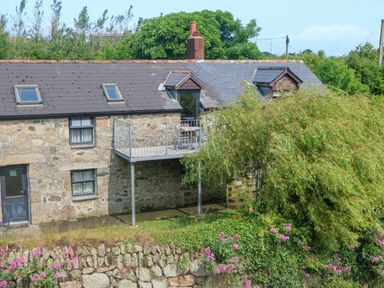 A stone building with a balcony and flowers at The Cottage in St. Ives