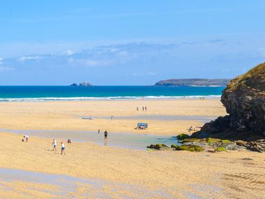 A beach with people walking and playing near water at The Cottage in St. Ives