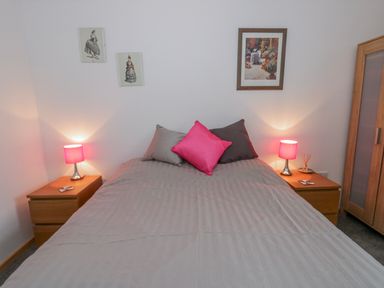 A bedroom with a bed, nightstands, and wall art at Yr Hen Ysgoldy