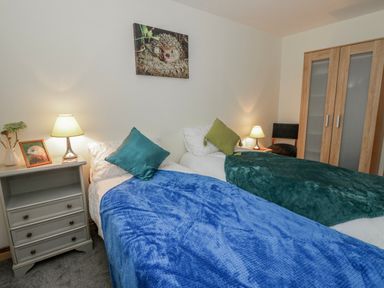A bedroom with two beds and a lamp at Yr Hen Ysgoldy in 
