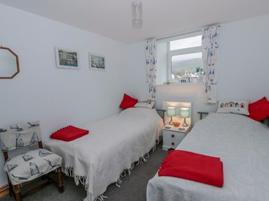 A bedroom with two beds and a bedside table at Yr Hen Ysgoldy
