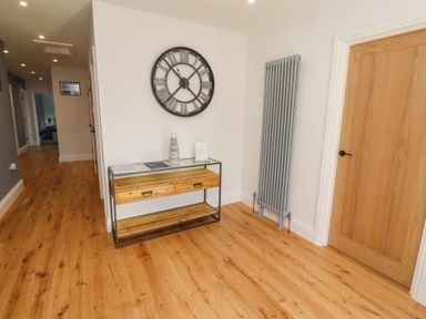 A hallway with a clock and console table at Rose Cottage in Dunstan near Embleton