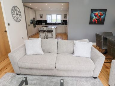 A living room with a sofa and dining area at Rose Cottage in Dunstan near Embleton