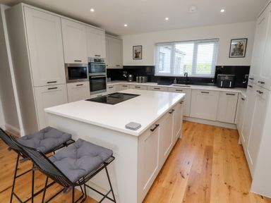 A kitchen with cabinets and an island at Rose Cottage Dunstan near Embleton