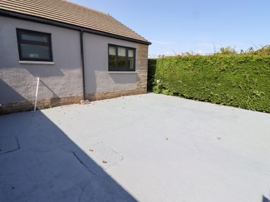 An outdoor area with a house exterior and concrete surface at Rose Cottage in Dunstan near Embleton