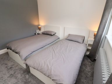 A bedroom with two single beds and bedside tables at Rose Cottage Dunstan near Embleton
