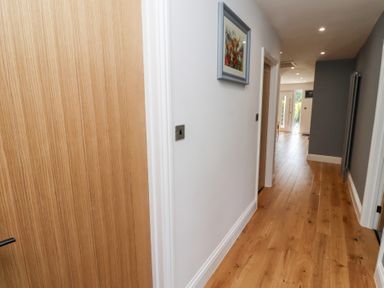 A hallway with a wooden door and artwork at Rose Cottage in Dunstan near Embleton