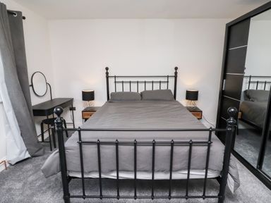 A bedroom with a bed, nightstand, lamp and desk at Rose Cottage in Dunstan near Embleton