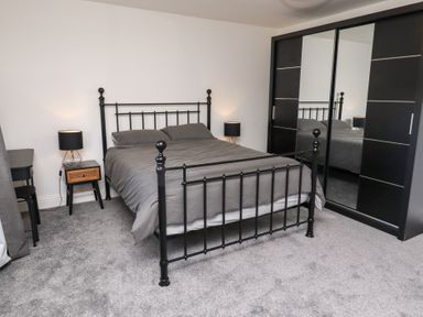A bedroom with a bed and mirrored wardrobe at Rose Cottage in Dunstan near Embleton