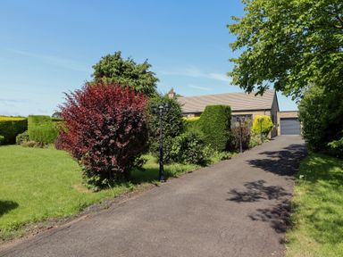 A house with a driveway and garden at Rose Cottage in Dunstan near Embleton