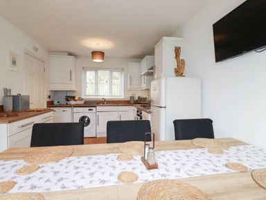 A kitchen with appliances and dining table at Poldam St Austell