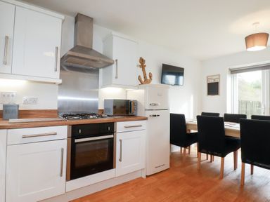 A kitchen with a gas stove and dining area at Poldam in St Austell