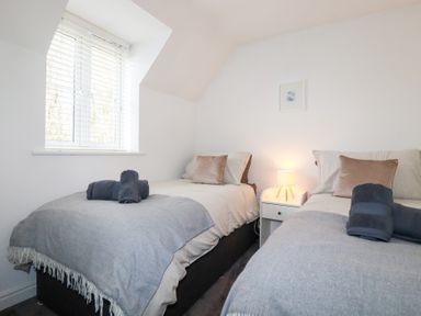 A bedroom with two beds and a lamp at Poldam in St Austell