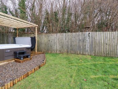 A garden with a hot tub and wooden deck at Poldam St Austell