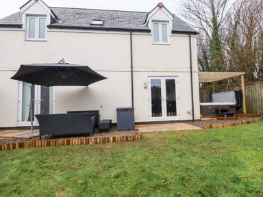 An outdoor seating area with a sofa and hot tub at Poldam in St Austell