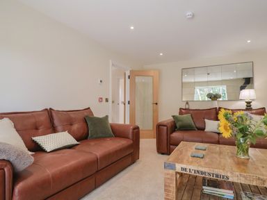A living room with brown sofas and a wooden table at Foxes Den, Pendomer near Yeovil, Somerset