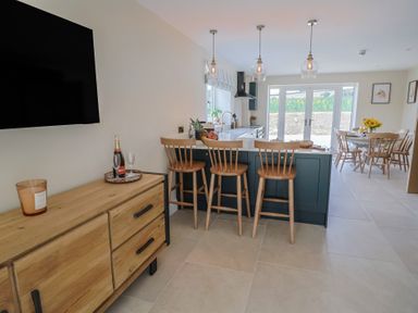 A kitchen with bar stools and a dining table at Foxes Den in Pendomer near Yeovil, Somerset
