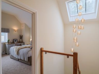 A landing with a staircase and light fixture at Foxes Den Pendomer near Yeovil, Somerset