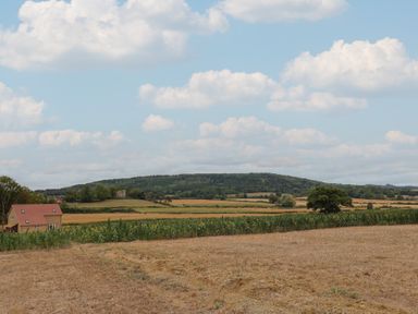 A landscape view with a house, fields, and hills at Foxes Den, Pendomer near Yeovil, Somerset