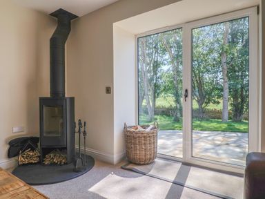 A snug with a wood stove and a basket at The Fox Den in East Coker