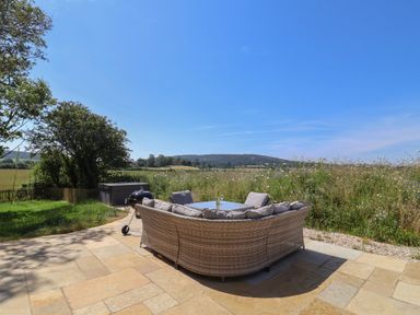 An outdoor seating area with a table and view of fields at The Fox Den in East Coker