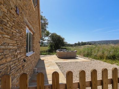 An outdoor area with a stone wall and seating at The Fox Den in East Coker
