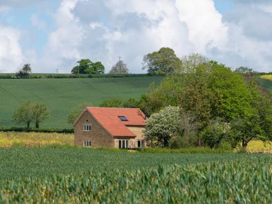 A house surrounded by fields and trees at The Fox Den in East Coker