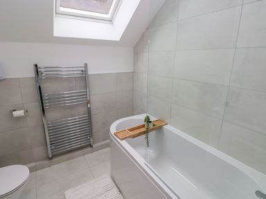 A bathroom with a bathtub and towel rail at Hafan Y Gof in Newcastle Emlyn