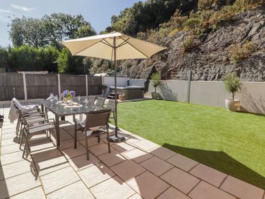 A garden with a dining table and chairs under an umbrella at Hafan Y Gof Newcastle Emlyn