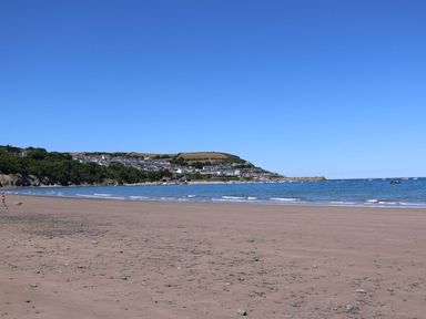 A beach with houses and hills in the background at Hafan Y Gof in Newcastle Emlyn