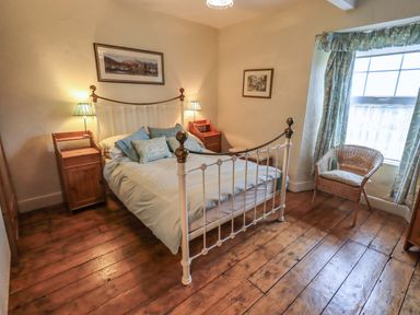 A bedroom with a bed and nightstands at Stoker’s Cottage in Windermere