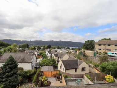 A view of houses and trees towards a lake and mountains at Stoker’s Cottage Bowness-On-Windermere