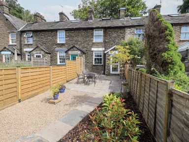 A garden with a table and chairs in Stoker’s Cottage in Bowness-On-Windermere