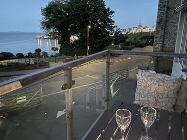 A balcony with glasses and a view of the ocean at 10 Croft Court in Tenby