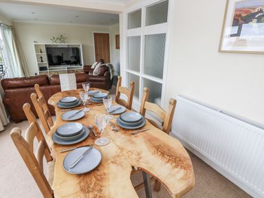 A dining room with a wooden table set for dinner at Lifeboat Lookout in Tenby